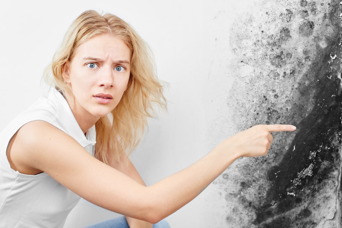 Verängstigte Frau zeigt auf Wand